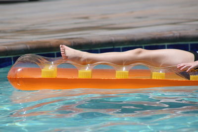 Low section of woman on pool raft on swimming pool