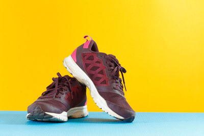 Close-up of sports shoes against yellow background