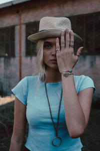 Portrait of woman wearing hat standing against built structure