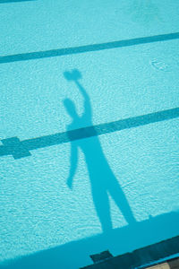 Shadow of man holding dumbbells seen in swimming pool