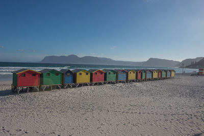 Multi colored hooded chairs on beach against clear sky