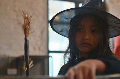 Close-up of girl wearing witch costume at home