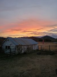Houses on field against sky during sunset