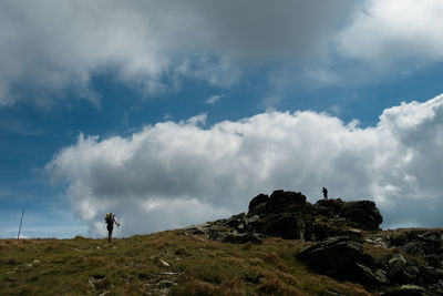 Low angle view of man standing on rock against sky