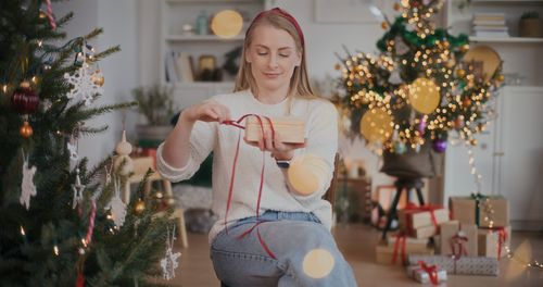 Portrait of smiling young woman holding christmas tree at home