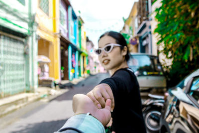 Cropped image of boyfriend holding girlfriend hand in city