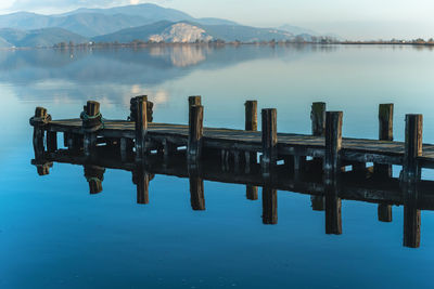 Wooden jetty reflected on the water of a blue lake massaciuccoli lake lucca