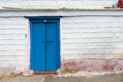 A blue door on a white wall with square shapes on it.