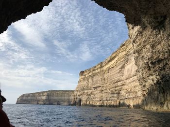 Sea by rock formation against sky