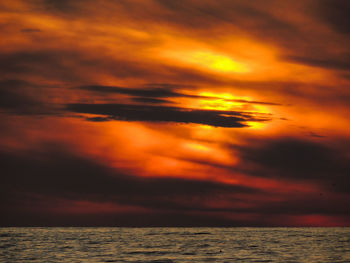 Scenic view of sea against dramatic sky during sunset