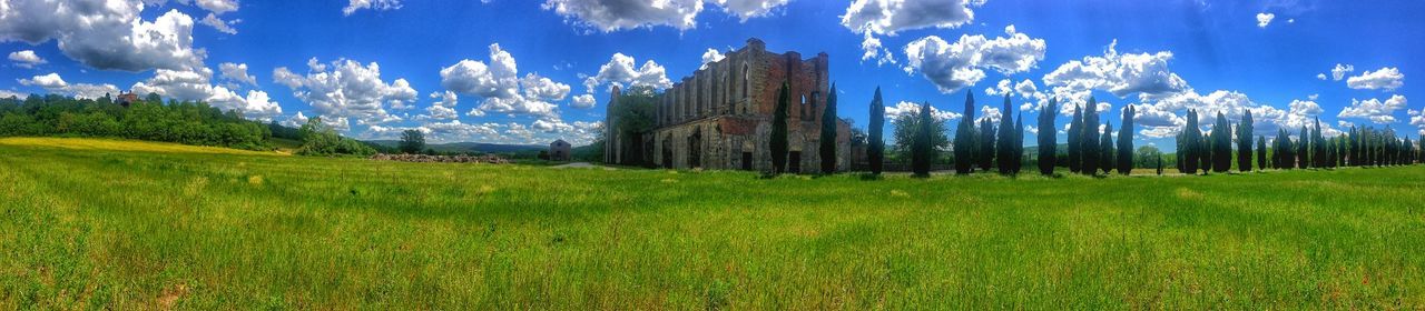 grass, sky, architecture, built structure, building exterior, blue, field, green color, landscape, cloud - sky, grassy, tranquility, sunlight, tranquil scene, cloud, nature, growth, beauty in nature, scenics, day