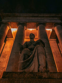 Low angle view of statue against historic building at night