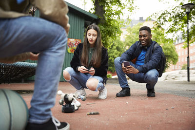 Friends controlling robot with smart phone while having battle at park