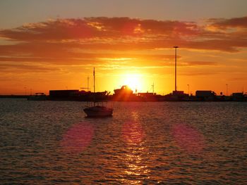 Silhouette boat sailing in sea against sky during sunset