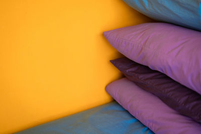 High angle view of pillow stack on bed by yellow wall