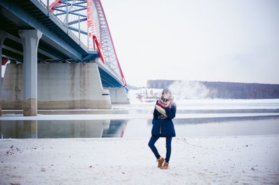 Full length of woman standing in snow against sky