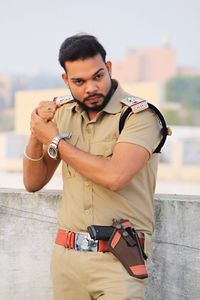 Policeman looking away while standing against sky