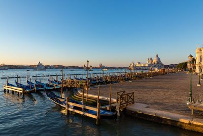 Sailboats moored in sea against clear blue sky