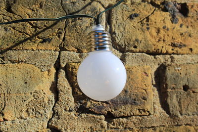 Low angle view of light bulb hanging on wall