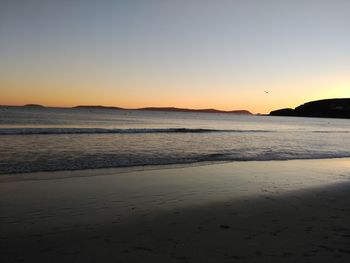 Scenic view of beach against sky at dusk