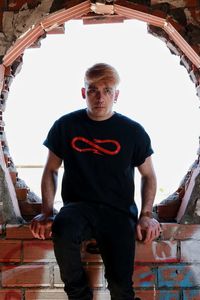 Portrait of young man standing against window