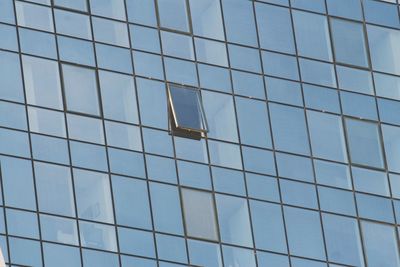 Low angle view of glass building against blue sky