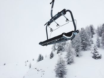 Ski lift on snow covered mountain against sky