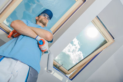 Low angle view of painter holding roller