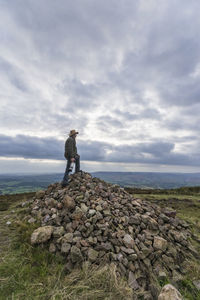 Thoughtful senior man standing on rocks against sky