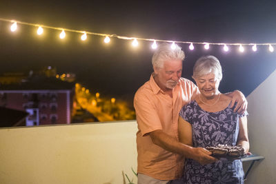 Man and woman standing against illuminated wall at night