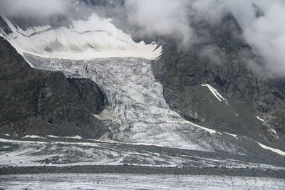 A glacier in the rocky mountains, a satellite of mount belukha in altai, with low clouds in summer