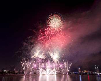 Low angle view of firework display over river against sky