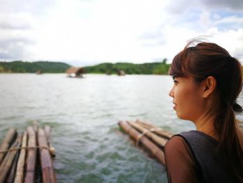 Portrait of young woman looking away against sky