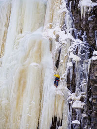 Rear view of man ice climbing