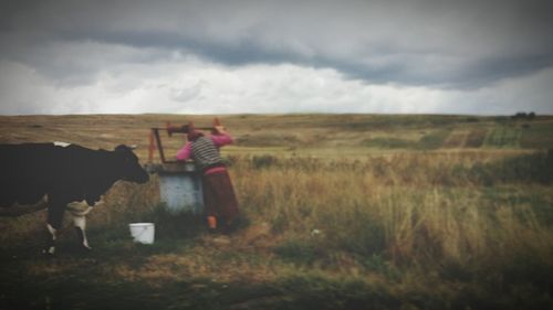 Woman standing on field against storm clouds