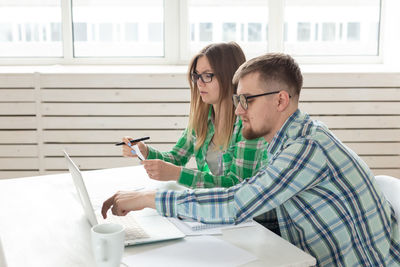 Young woman using mobile phone while sitting in office