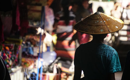 Rear view of woman wearing asian style conical hat in market