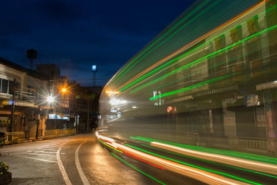 Light trails on road against sky at night