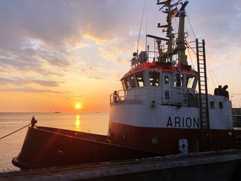 Ship moored in sea against sky during sunset