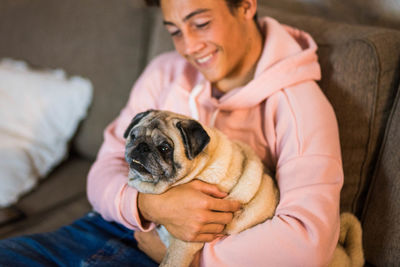 Midsection of boy with dog sitting on bed