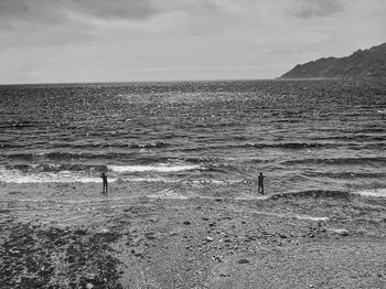 Silhouette man standing on beach against sky