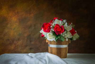 Red roses and white roses artificial on a brown background with space for text input.