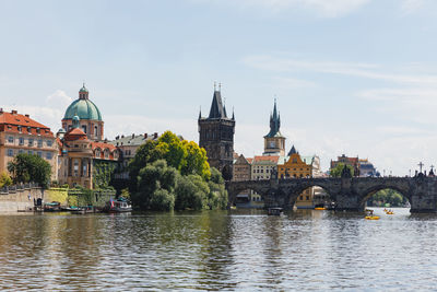 Bridge over river by buildings in city against sky