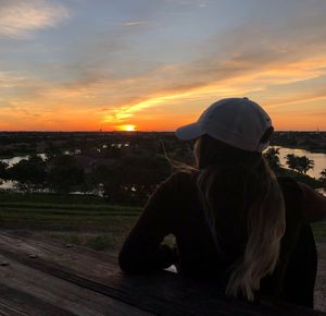 Woman sitting against sky during sunset