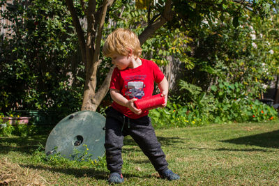 Full length of boy holding while standing by tree