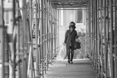 Woman carrying plastic bag on footbridge