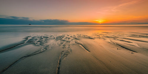 Scenic view of beach against sky during sunset