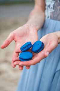 Midsection of woman holding blue macaroons