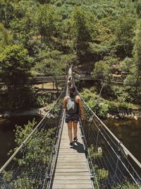 Rear view of women on footbridge in forest