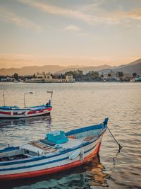 Boat moored on sea against sky during sunset